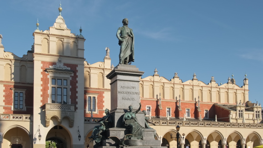 Statue of Adam Mickiewicz and Sukiennice buidning with Town Hall at the background on Market square in Cracow, Poland. Slow steadicam tracking shot. On monument written: To Adam Mickiewicz from people 