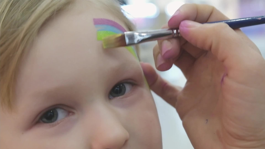 Artist painting a rainbow on girl