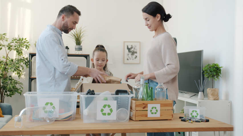 Slow motion of mother father and daughter sorting out recyclable waste putting in boxes indoors at home. Environment and ecology concept. Royalty-Free Stock Footage #1092343545