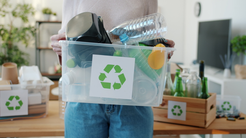 Close-up of full recycling box with plastic containers and woman holding it at home. Environment protection and pollution concept. | Shutterstock HD Video #1092343563
