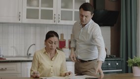 Young married couple checking payment bills in kitchen at home. They manage the family budget, discuss spending money, have problems with payments. They calculate double bills, they experience stress. - Powered by Shutterstock - Get 15% off with code: PIKWIZARD15