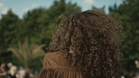 Camera tracking smiling young caucasian woman with curly hair dancing at music festival. Shot with RED helium camera in 8K. 