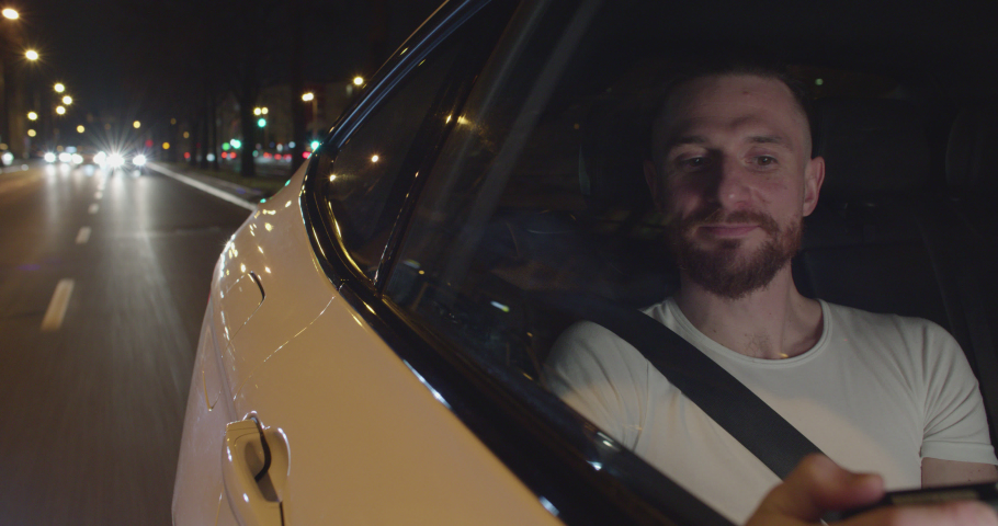 Handome male is traveling by uber car through the city looking out the window