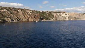 Video from a drone, a bay with a high rocky seashore and drifting yachts on the water. aerial view