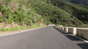 4K POV footage of driving along empty winding road through beautiful rocky mountain landscape. 4K motion video during sunny day. Highland of Anaga park, Tenerife island, Spain. Wide angle footage
