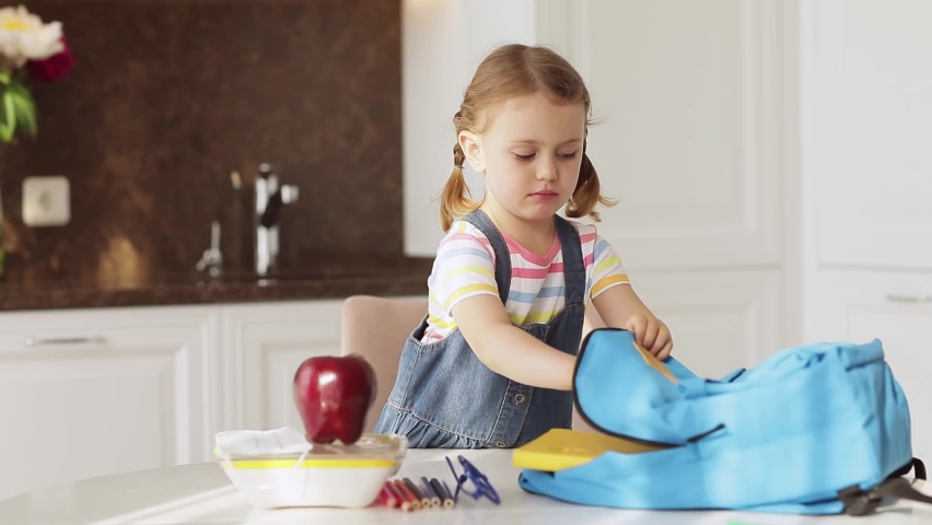 Toddler girl preparing backpack for school at home at table on sunny morning kitchen.Education,learning.Back to school. get ready for school schoolbag Royalty-Free Stock Footage #1092358363