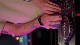 DJ working on console in club. Closeup male hands twist the buttons on the control console and change the music tones. Nightlife and party concept. Slow motion vertical video
