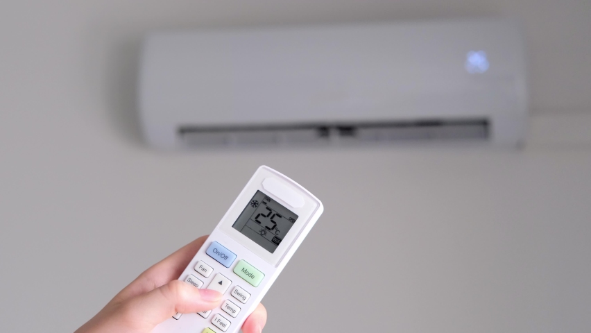 Setting comfortable air temperature on the air conditioner using the remote control. Slow motion Royalty-Free Stock Footage #1092361971