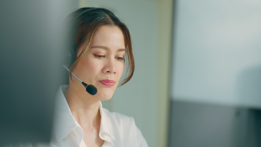Asian beautiful business woman call center working in office workplace. Attractive young female employee worker sit on table wearing headset and use laptop computer talk to support customer in company Royalty-Free Stock Footage #1092363411