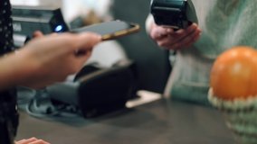 Video of close up of woman paying for the purchase with her smartphone via NFC in a grocery store.