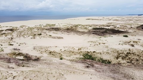 Picturesque drone view of arid sandy Curonian Spit located near Baltic Sea against cloudy blue sky
