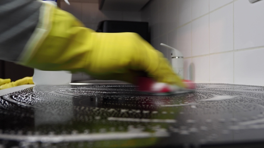 Cropped view of man washing electric stove.