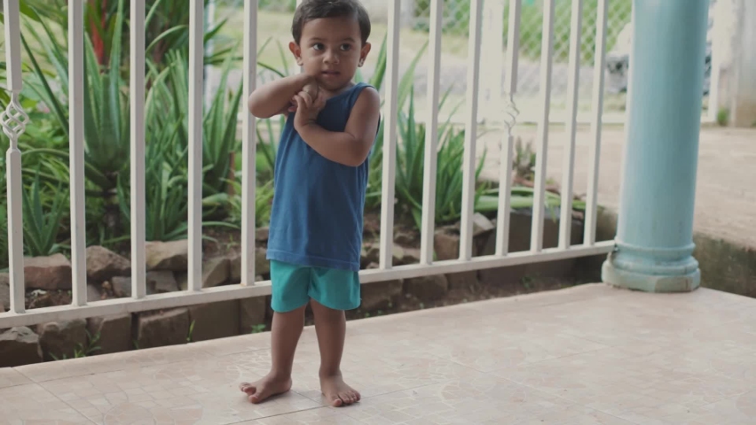Latino boy looking through the white railings, in the house, wide shot