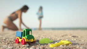 Many bright multi-colored plastic toys lie on a large sea sandy beach near the blue stormy mysterious sea under the warm summer sun