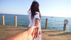 Follow me challenge for couple holds hand of man. Rear view beautiful young woman smiles and runs on wooden pier with sun beds by sea. Summer walk on vacation on weekend. Adventure tourist lifestyle. - Powered by Shutterstock - Get 15% off with code: PIKWIZARD15