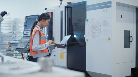 Research and Development Specialist with a Laptop Comes Up to Operate a Heavy Industry Machine at a Factory. Asian Female Technician Configuring Industrial Machinery with the Help of Computer.