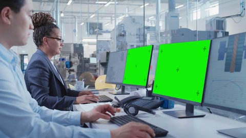 Factory Office Facility: Industrial Engineers Drafting Blueprints of a Heavy Industry Machine Parts on a Computer CAD Software. One Computer Monitor Display is a Green Screen Mock Up Template.