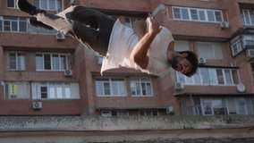 Male parkour athlete performs a trick with overcoming obstacles. Does somersault with a screw against the background of a city building. Slow motion. - Powered by Shutterstock - Get 15% off with code: PIKWIZARD15