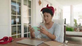 African american woman playing video game sitting on table at home terrace