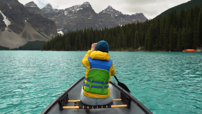 Tourist woman exploring the Canadian Rockies, paddling a canoe on Moraine Lake during summer in Banff National Park, Alberta, Canada. Royalty-Free Stock Footage #1092398283