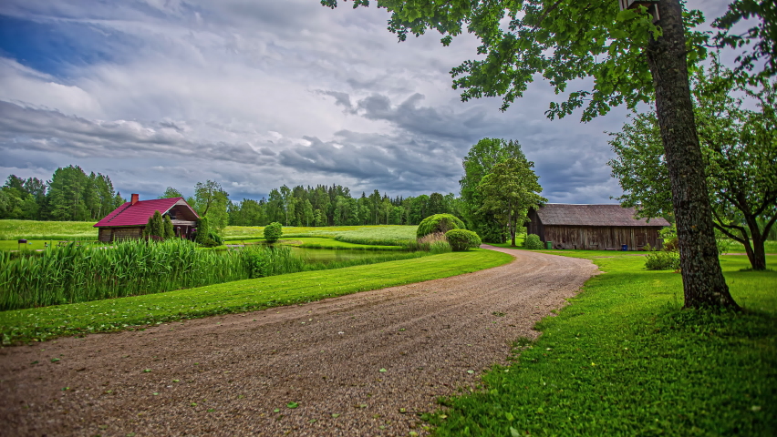 Picturesque countryside farmhouse, barn and fields with cloudscape overhead - time lapse