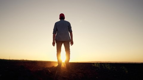 Agriculture. farmer at sunset walk on fertile soil. Farm worker silhouette. The foot of a man in rubber boots walk through the mud. Farmer agronomist works on land plot at sunset. Agriculture concept