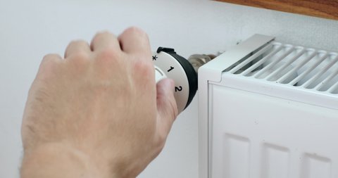 Man hand changing the temperature on the radiator by temperature controller