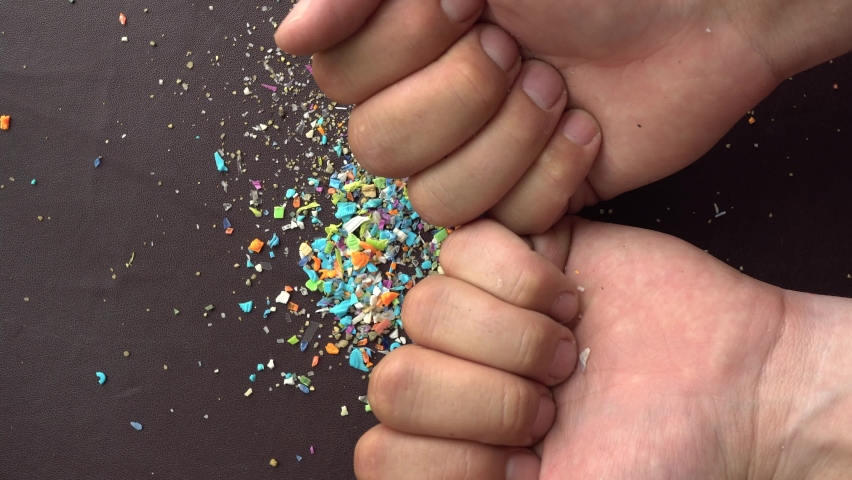 Close-up of microplastic particles falling into person's hand. The concept for water pollution and global warming. Macro shot on a bunch of microplastics that cannot be recycled | Shutterstock HD Video #1092405189