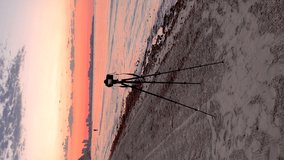  Video of a camera on a tripod taking pictures at sunrise on the beach, because it is the photography day.
