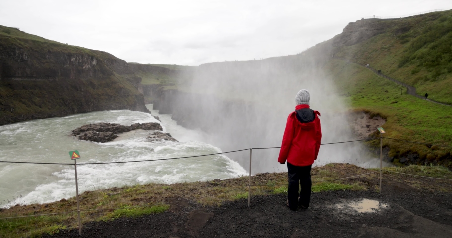 Gulfoss waterfalls in Iceland with gimbal video walking behind woman looking at falls.