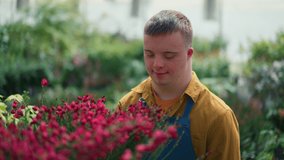 Happy young employee with Down syndrome working in garden centre, taking care of flowers. - Powered by Shutterstock - Get 15% off with code: PIKWIZARD15