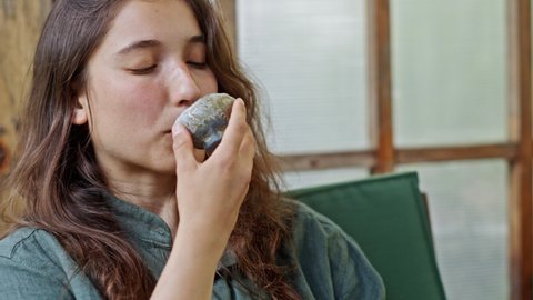 Young woman stares at small stone cup and drinks tea closeup. Young woman discovers small handmade Japanese stone cup and takes sip of tea. European lady wants to learn more about tea ceremony closeup