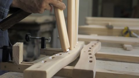 Slow motion. A professional carpenter takes a close-up of the details of furniture made of wood together.Assembling furniture in a carpentry workshop. Wood products for home decor.Lifestyle