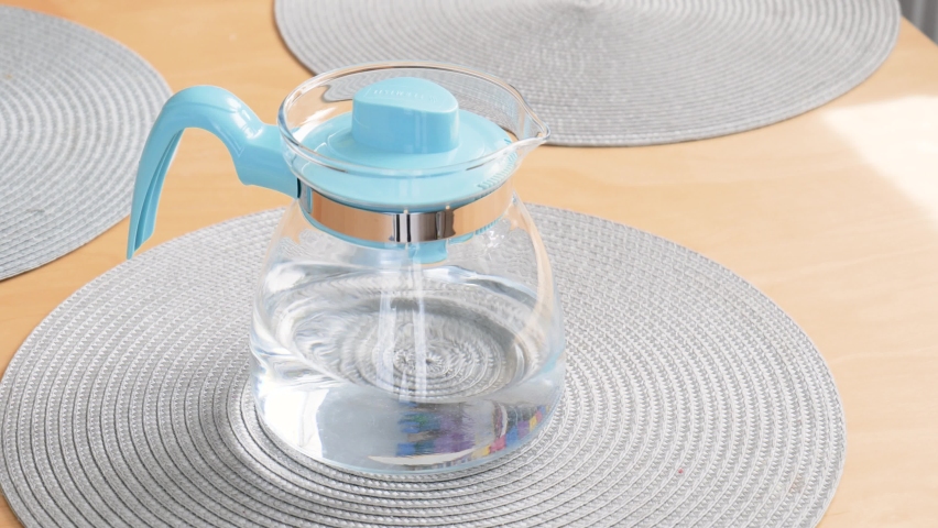 Krakow, Malopolska, Poland - April 2022: One modern light blue transparent jug full of clean fresh filtered drinking water laying on the table object closeup, nobody, no people. Drinking water concept