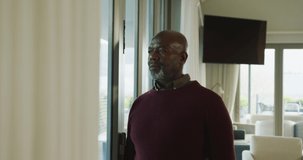 Video of lonely thoughtful senior american african men in living room. Retirement lifestyle, spending time alone at home.