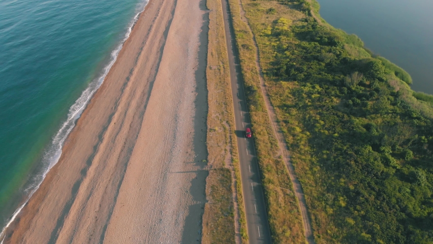 Aerial drone shot of cars driving along a scenic ocean highway | Shutterstock HD Video #1092424133
