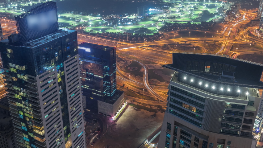 Aerial skyline with Golf Club, junction, hotels and residential areas far away in desert in Dubai night timelapse, UAE, top view from Dubai marina skyscrapers