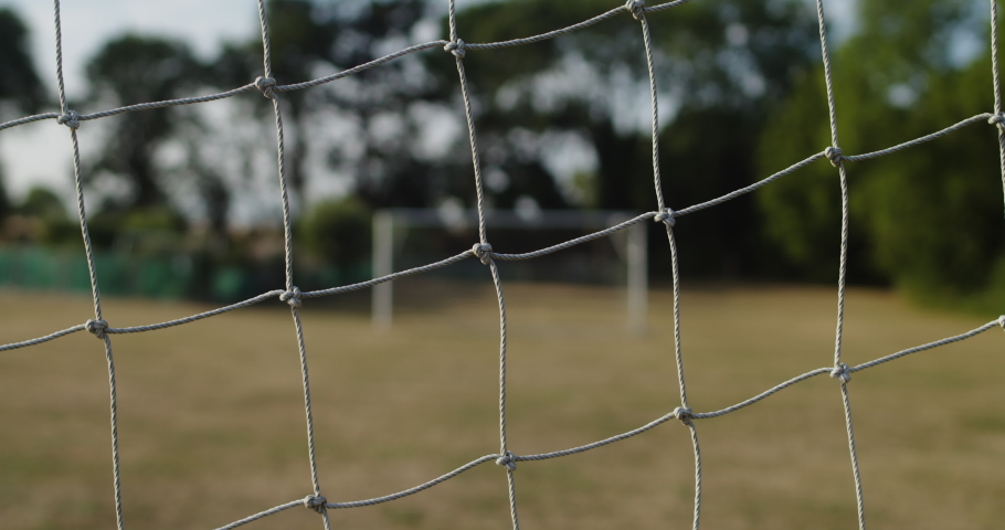 A CLOSE UP SHOT of a football goal net, football goal posts in the background. Royalty-Free Stock Footage #1092437487