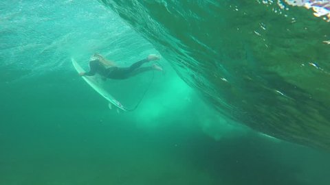 SLOW MOTION UNDERWATER: Young pro surfer girl doing duck dive