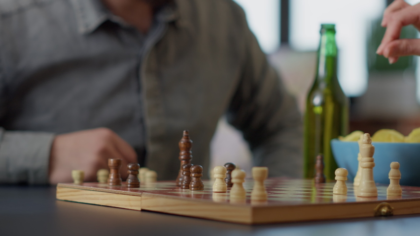 Man and woman playing strategic competition with board games, having fun with beer and chips. Young people enjoying positive gameplay match in living room. Handheld shot. Close up. Royalty-Free Stock Footage #1092444475