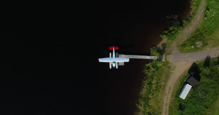 Aerial view above a seaplane docked at the coast of lake Inari, Finland - top down, drone shot