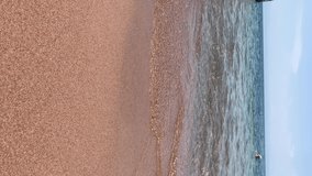 Sea waves roll on the sandy shore. Summer vacation and a walk to the sea. Nice weather for swimming. A storm or storm is coming. Vertical video