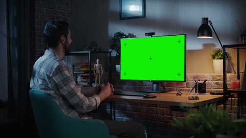 Creative Specialist Chatting on Video Call on Desktop Computer with Monitor with Green Screen Mock Up at Home Living Room. Freelancer Calling Client to Discuss Edits Online Over Internet.