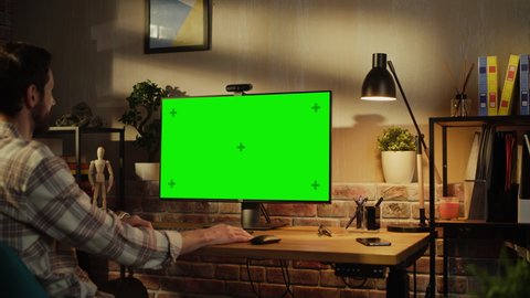 Project Manager Working Remotely from Home, Having a Video Call on Desktop Computer with Monitor with Green Screen Mock Up. Man Sitting in Living Room, Chatting with Business Partners and Clients.