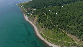 Aerial video footage of a green forest and houses on the lake. Road along the coast. Observatory. Human and nature. Top view.