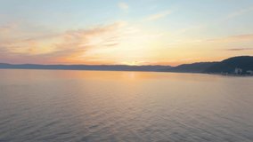 Aerial footage of flight over the sea at sunset. Ripples on the water. Coast. Top view. Clouds. Drone footage. 