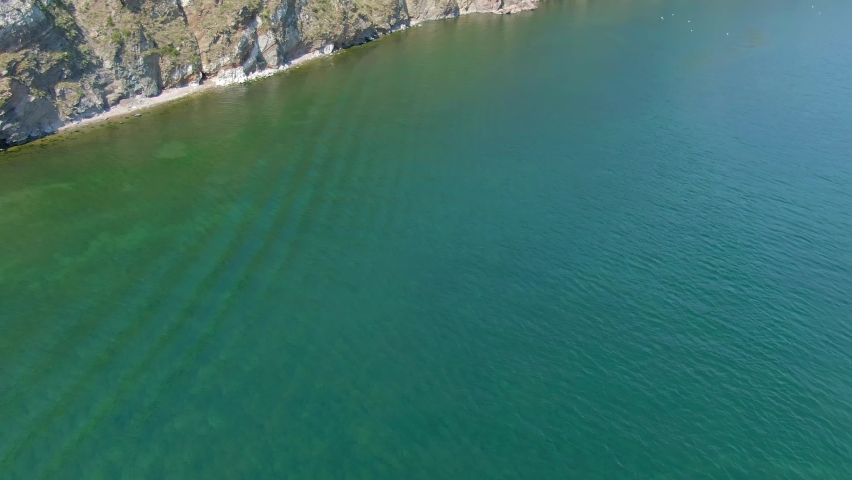 Rocky shore of lake Nature. Landscape. Blue water surface. Aerial drone video footage. Top view. 