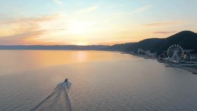 Motor boat at sunset floats on Lake Baikal. Seafaring. Water surface. Top view. Follow the boat. Aerial drone footage