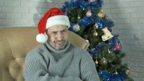 Stressed man at christmas eve at home. A man with life problems sits in loneliness during Christmas holidays in the room.