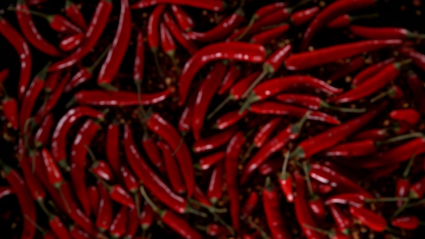 Super slow motion of exploding chilli peppers isolated on black. Overhead view, filmed on high speed cinema camera, 1000 fps. Ultimate perspective and concept of flying food. Royalty-Free Stock Footage #1092466509